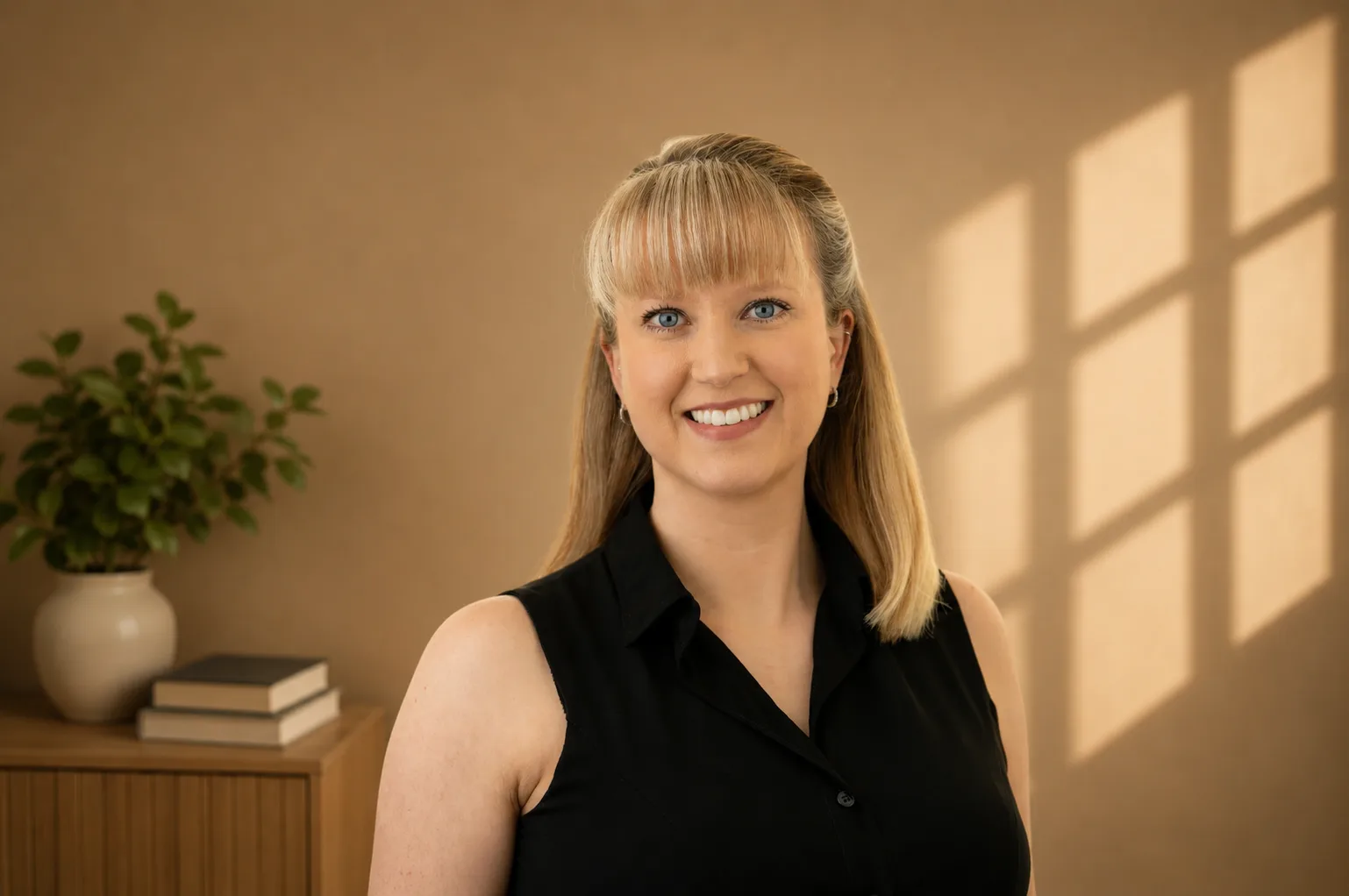 Blonde woman in black sleeveless top smiling in softly lit room