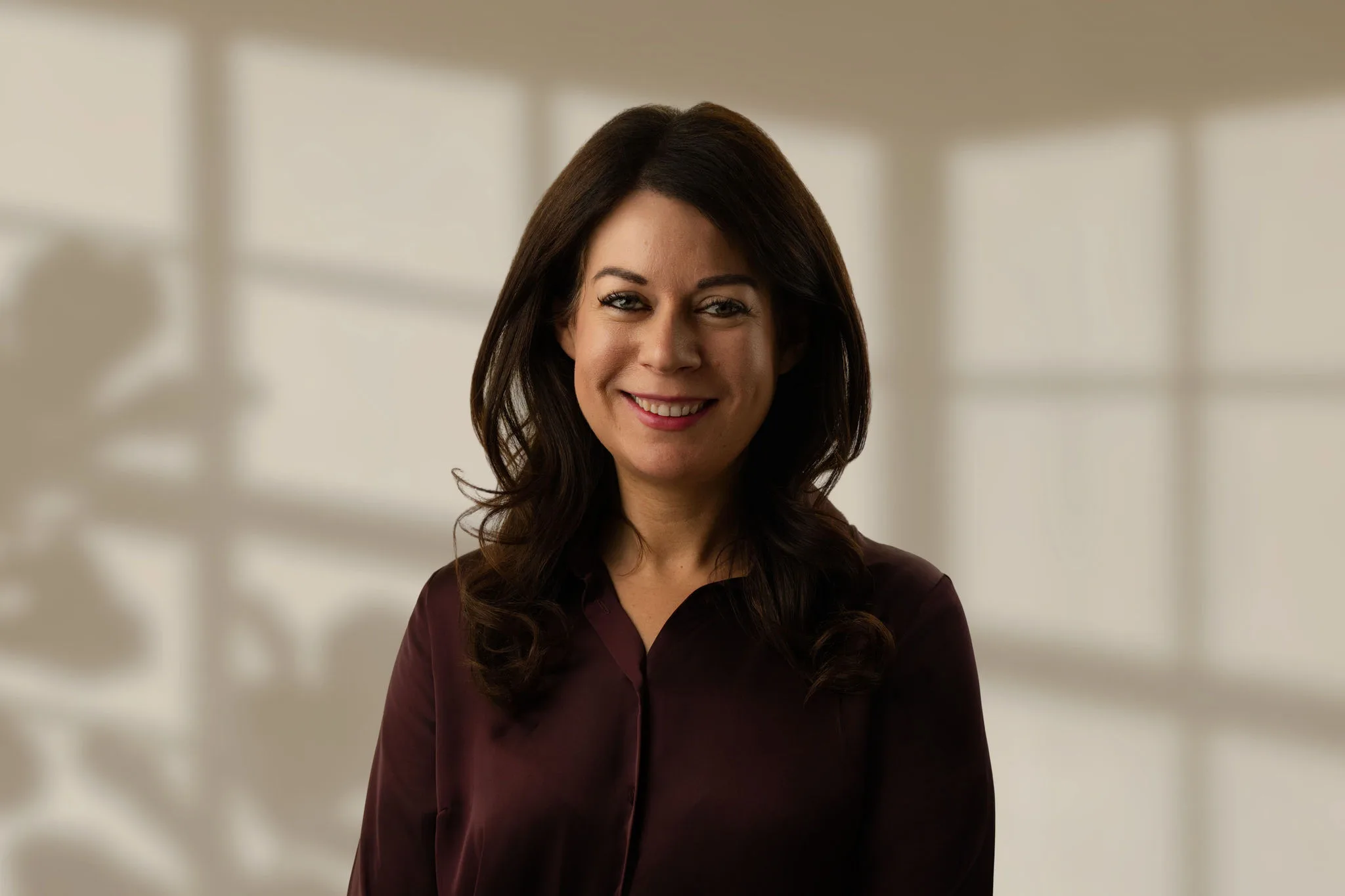 Woman with dark hair smiling against a softly lit background