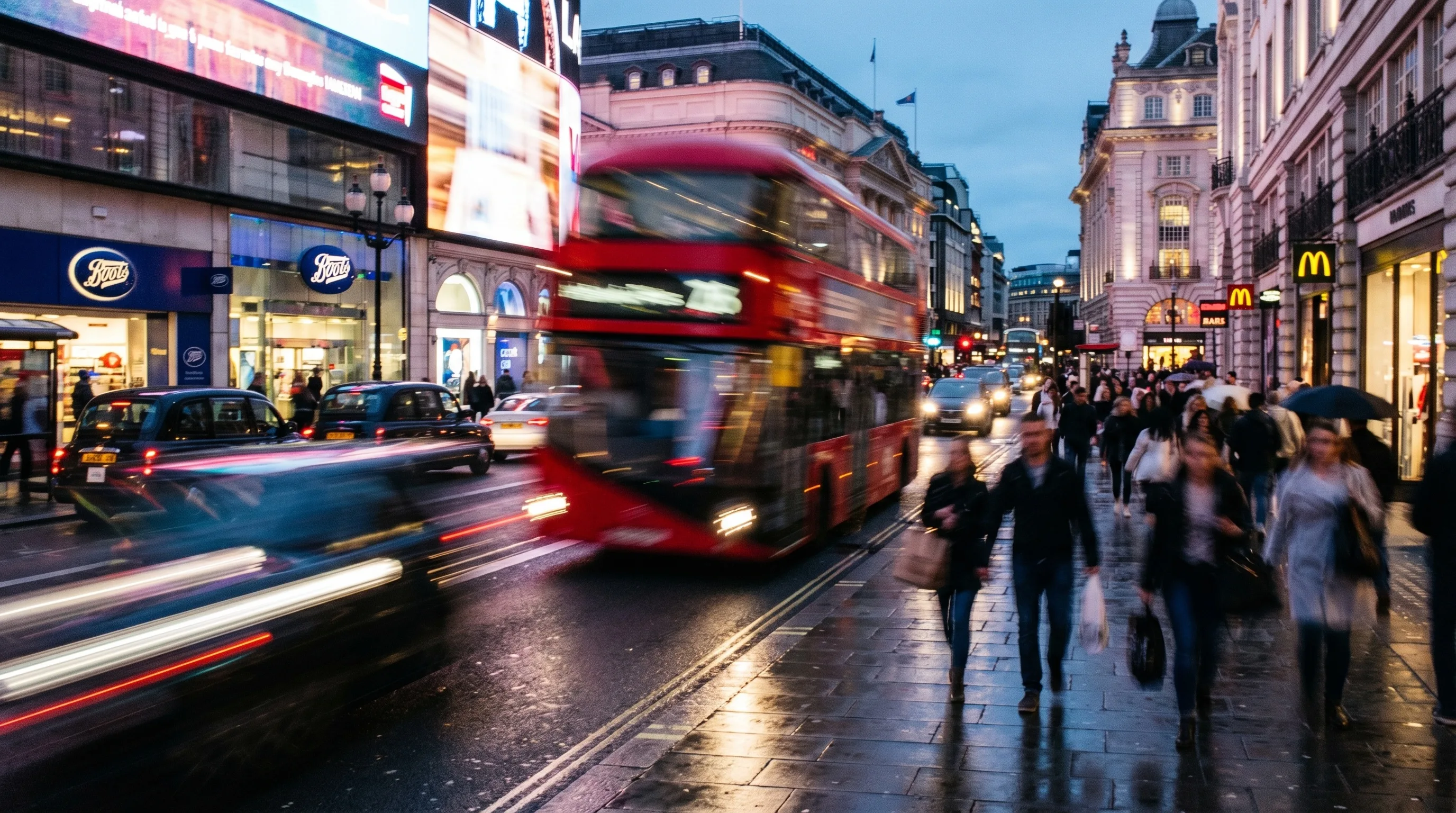 Blurred red double-decker bus and pedestrians on wet city street at dusk