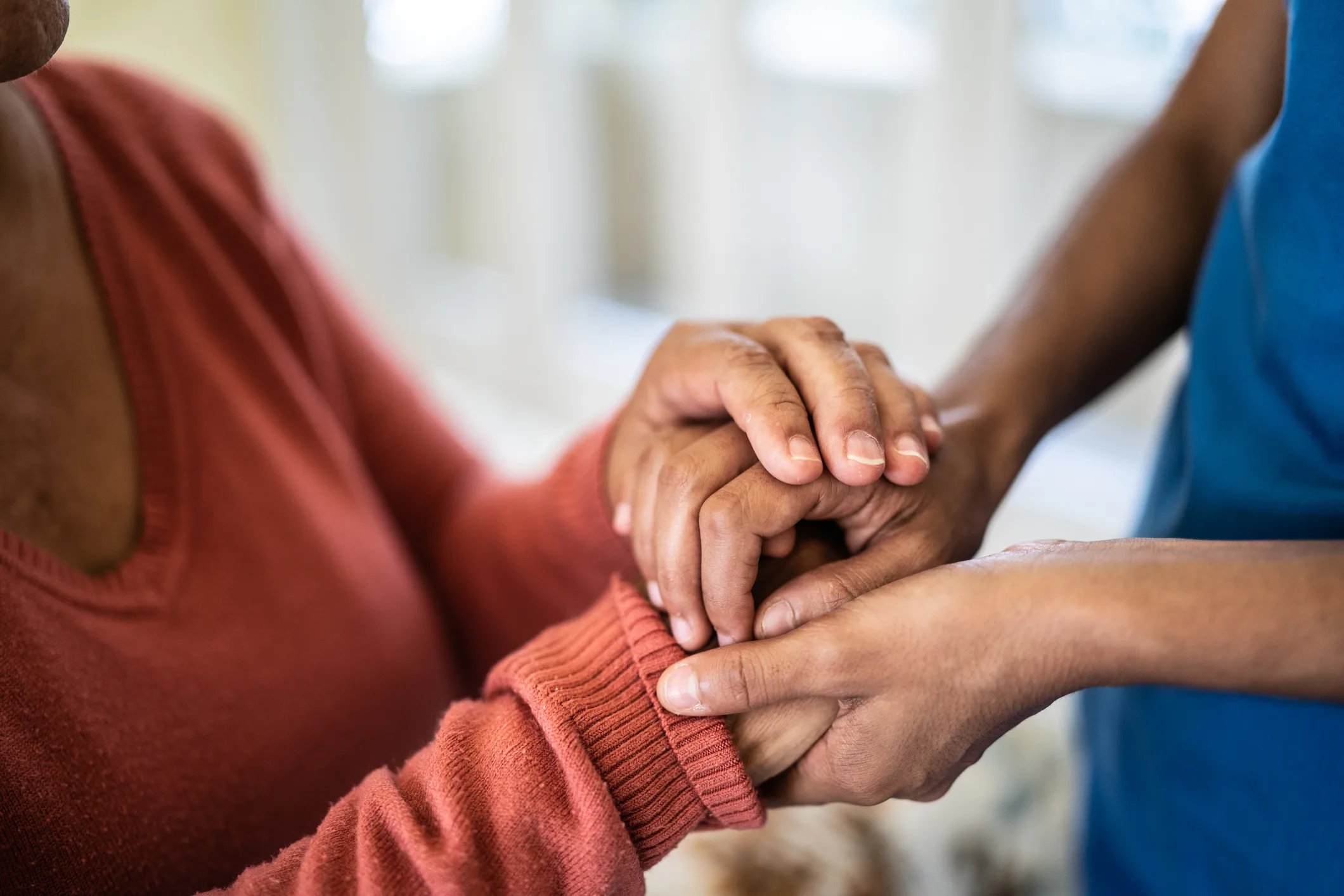Close-up of two pairs of hands gently holding each other