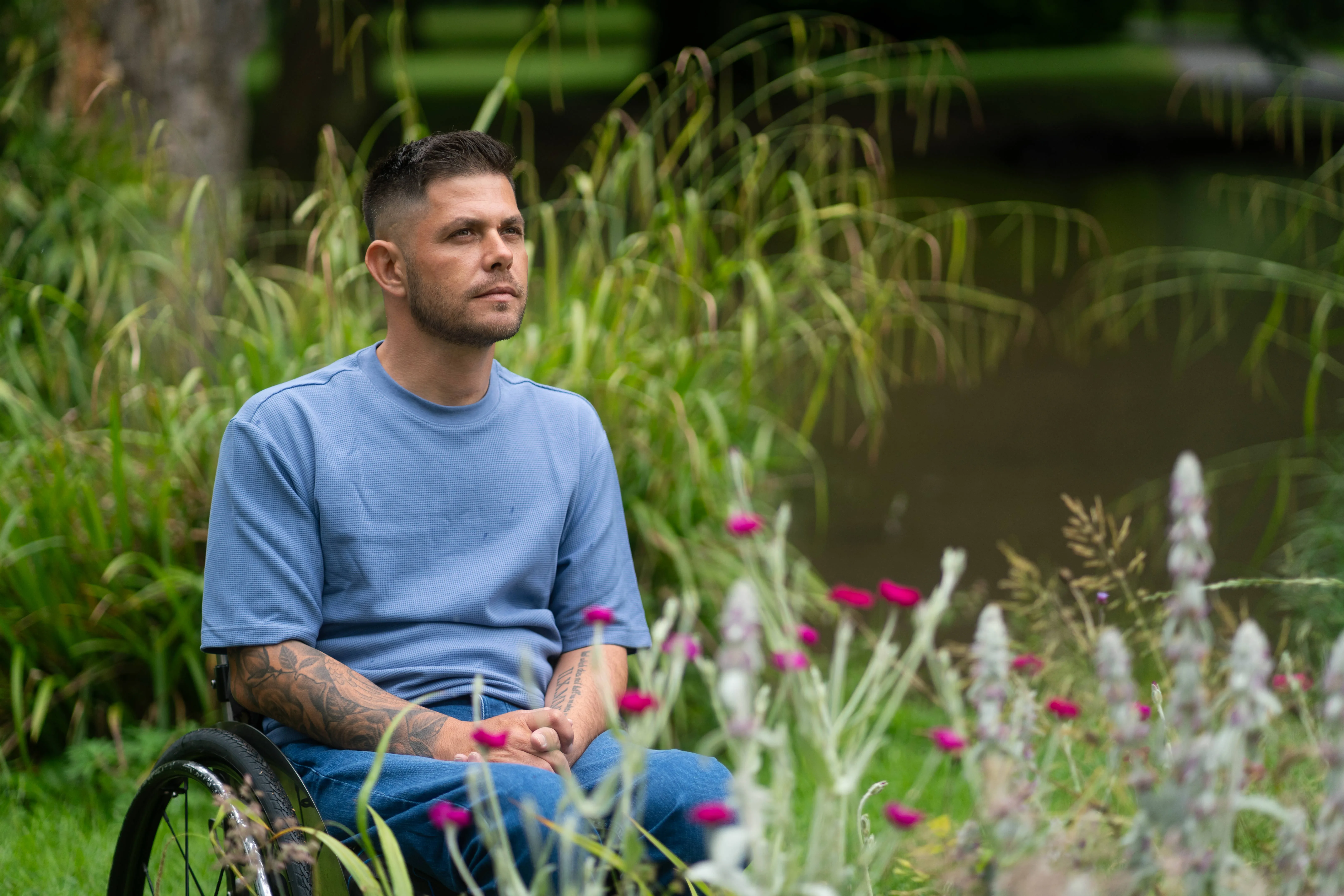Man in wheelchair sitting outside surrounded by plants and flowers