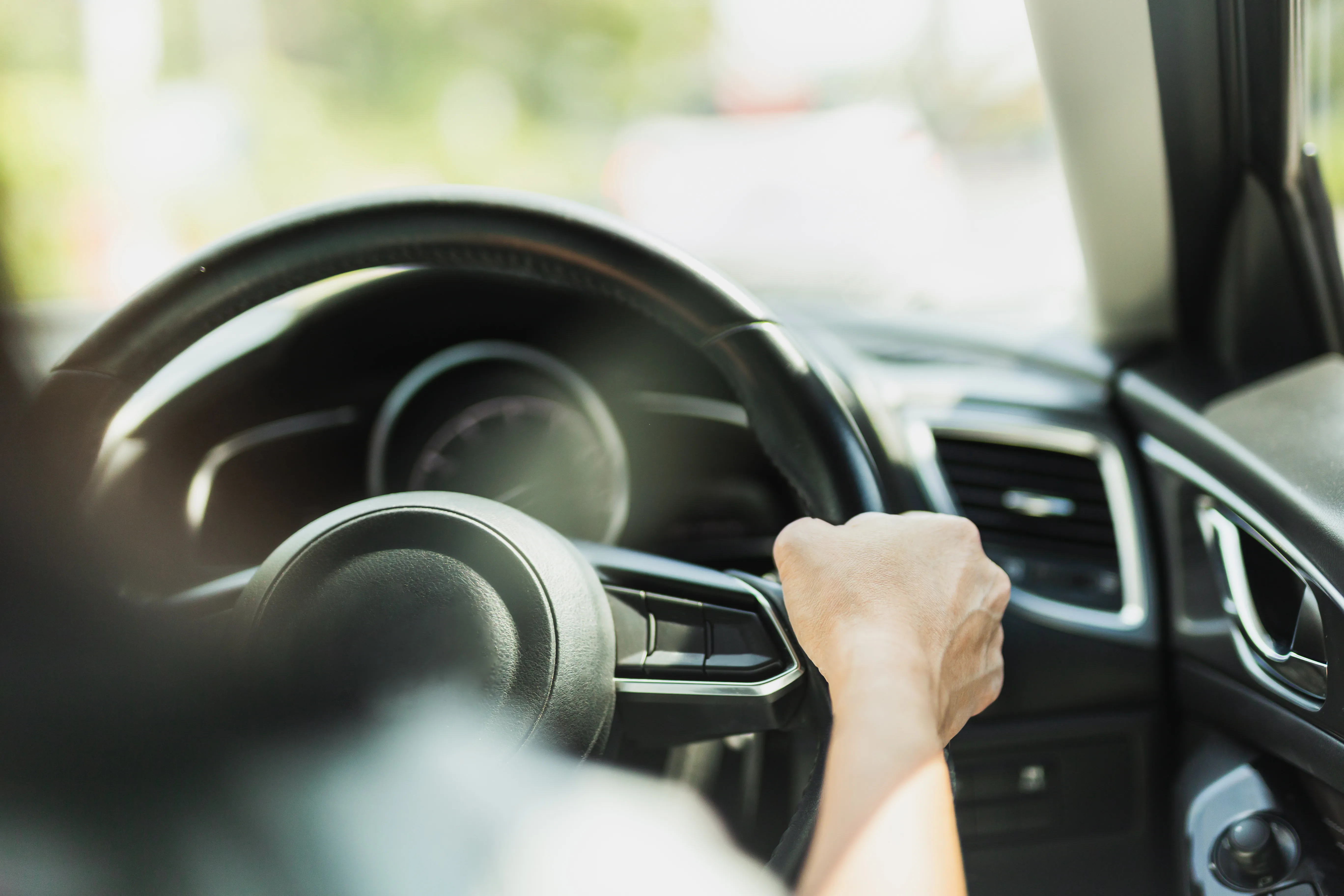 Close-up of person gripping a steering wheel while driving