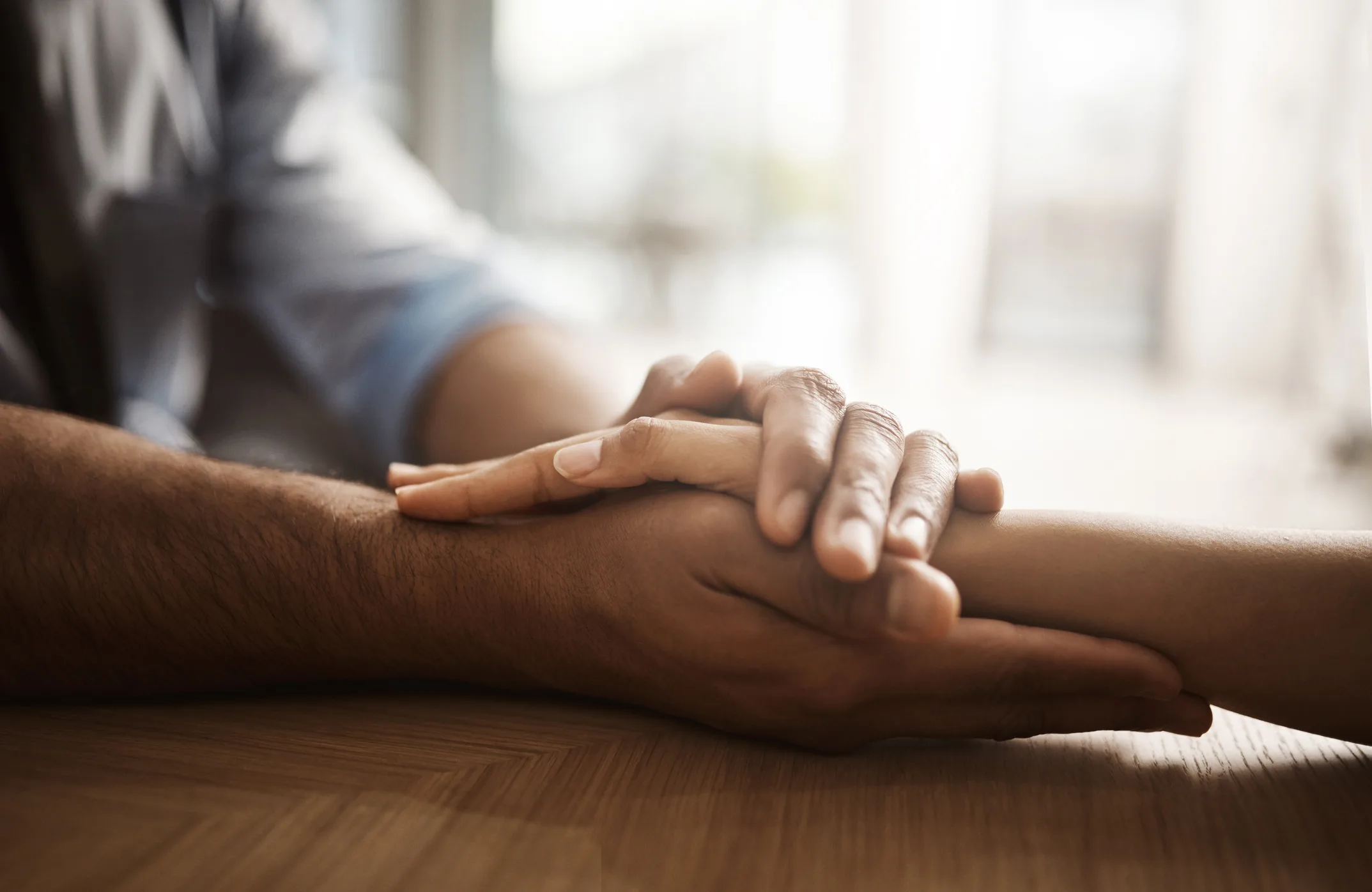 Two people holding hands on a wooden table