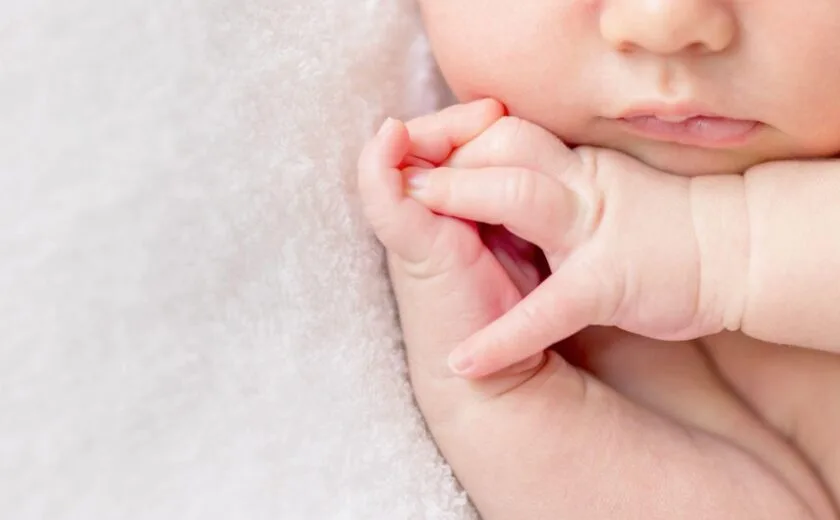 Baby holding adult finger close-up