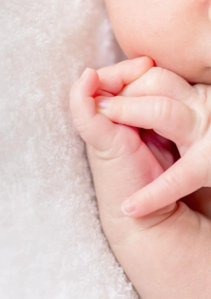 Baby holding adult finger close-up