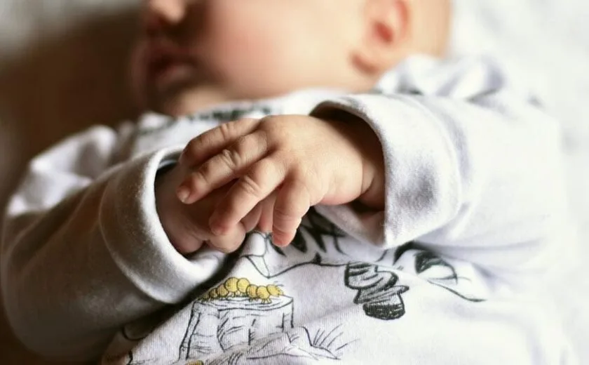 Baby lying down with hands clasped