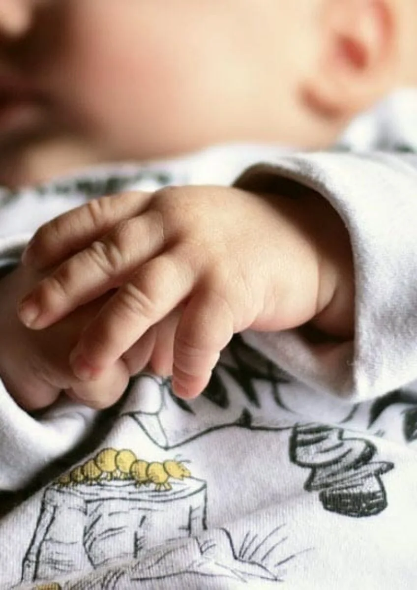 Baby lying down with hands clasped