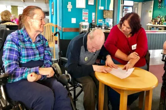 Care home staff helping residents at table