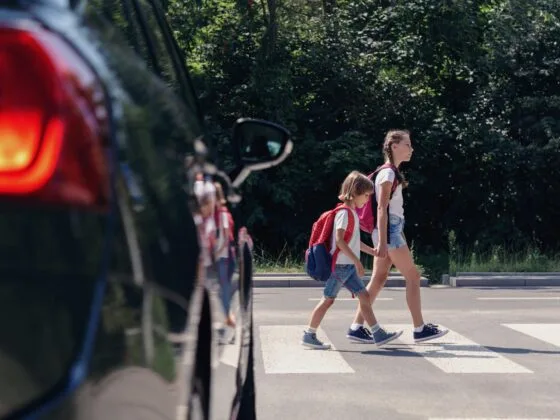 Children crossing road near parked car