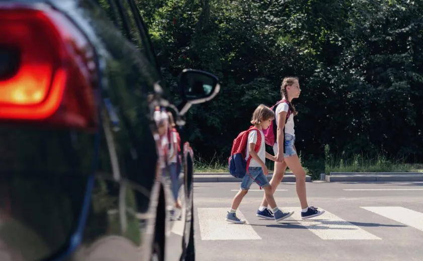 Children crossing road near parked car