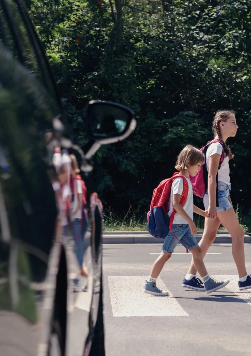 Children crossing road near parked car