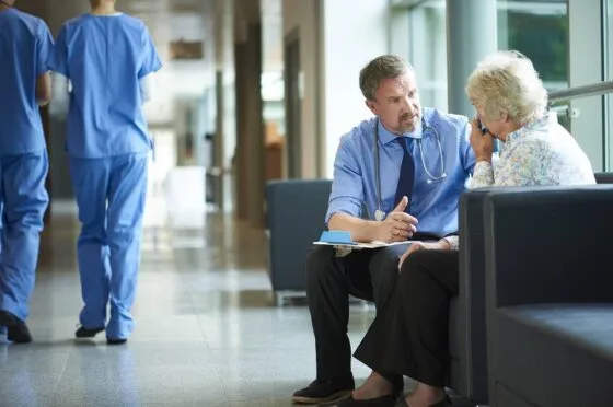 Clinician consulting older patient in hospital corridor