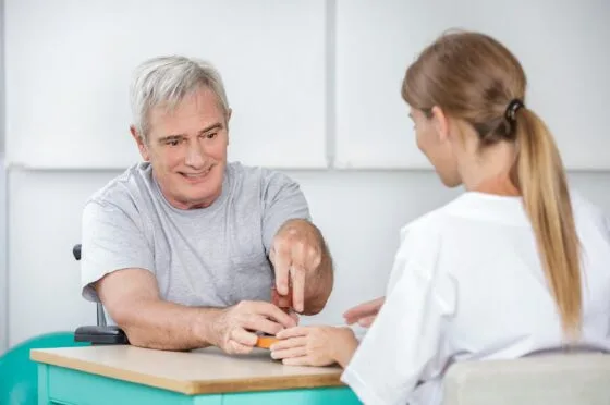 Clinician supporting man during hand therapy