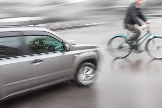 Cyclist riding beside passing car
