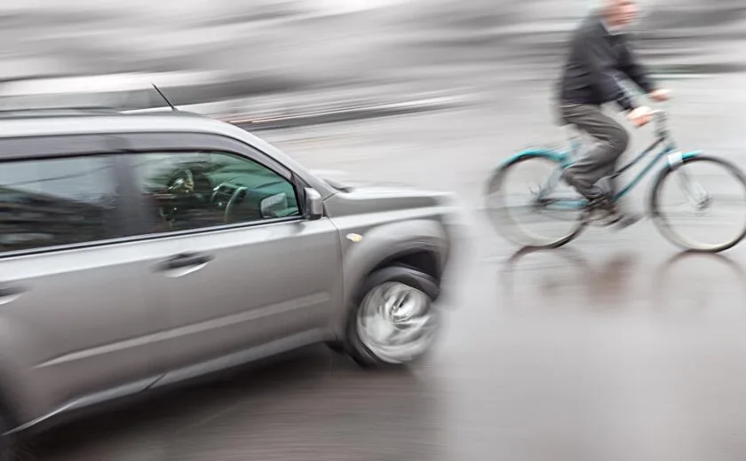 Cyclist riding beside passing car