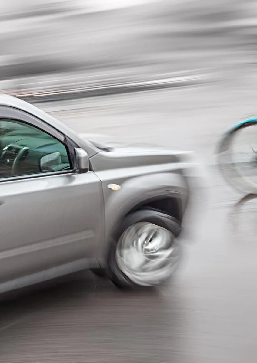 Cyclist riding beside passing car