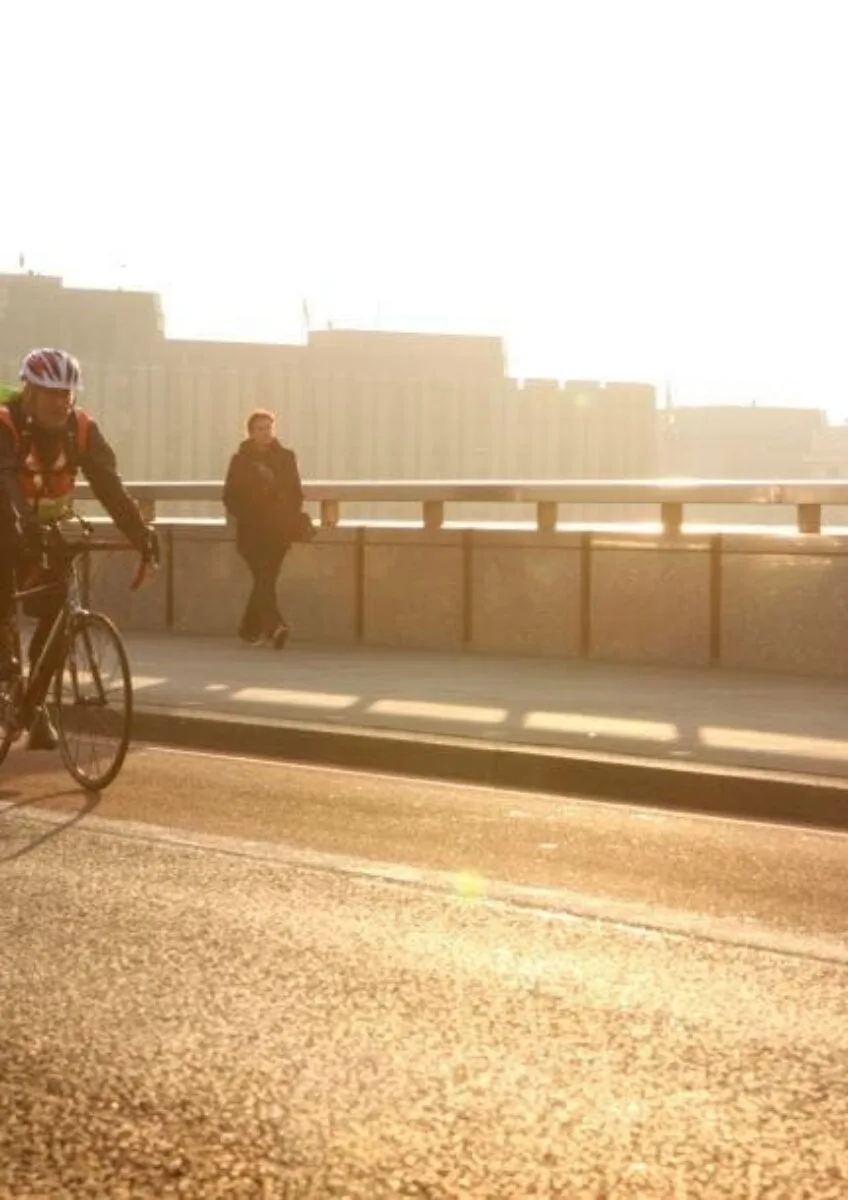 Cyclist riding over bridge at sunset