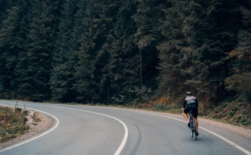 Cyclist riding through forest bend