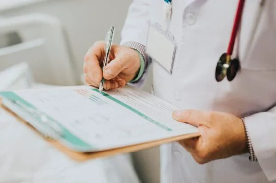 Doctor completing patient notes on clipboard