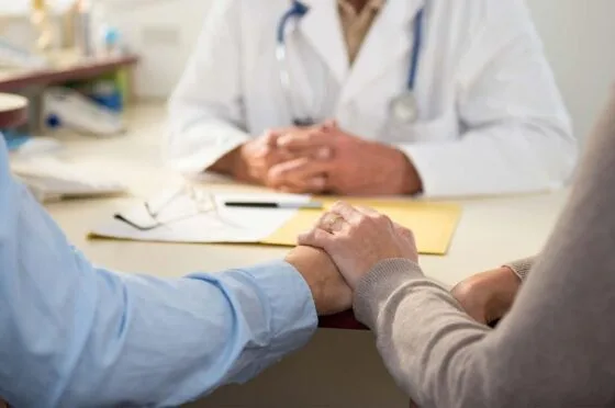 Doctor holding patient's hand during consultation