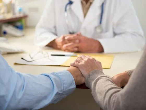 Doctor holding patient's hand during consultation