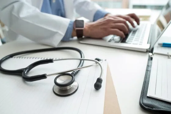 Doctor typing at desk with stethoscope