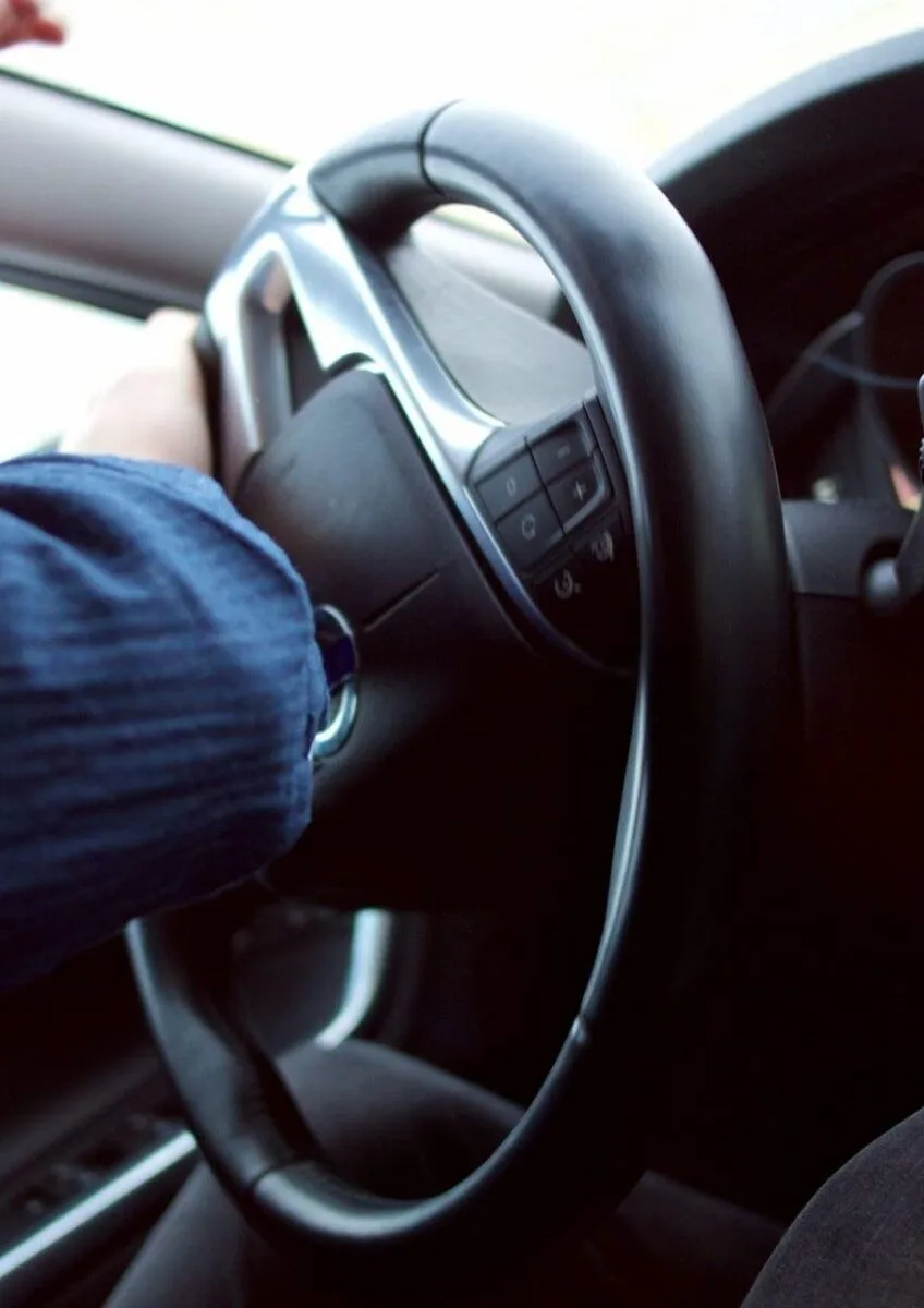 Driver holding steering wheel on road