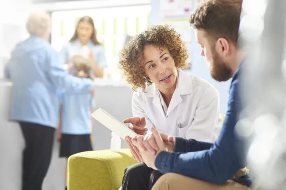 Healthcare professional speaking with patient in clinic waiting area