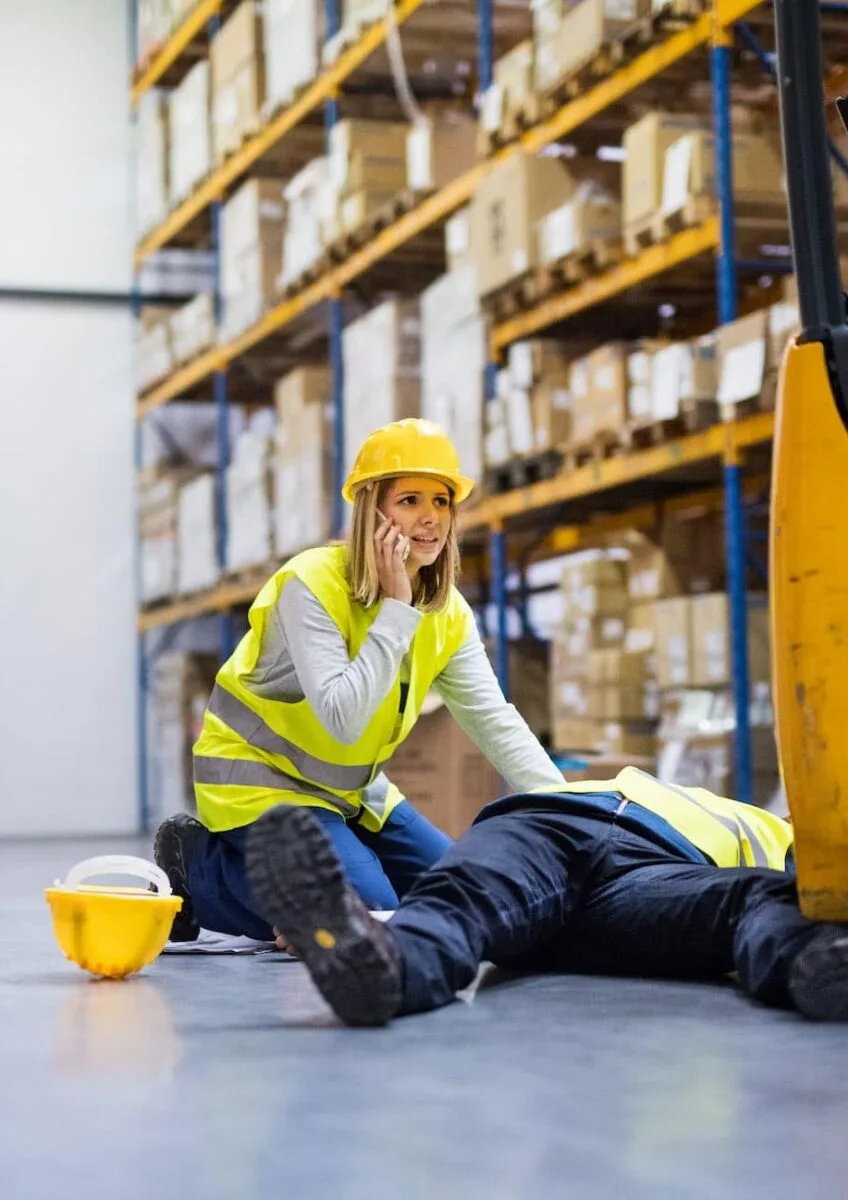 Injured warehouse worker beside forklift
