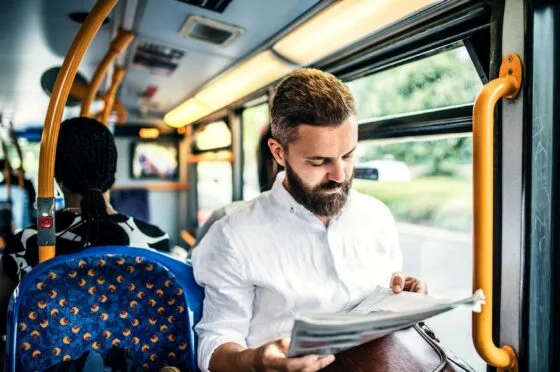 Man reading newspaper on bus