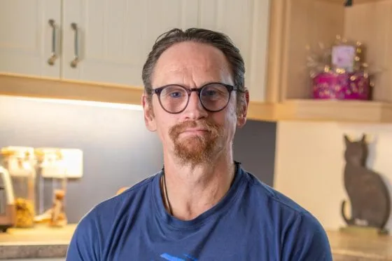 Ian Westmoreland with glasses seated in kitchen