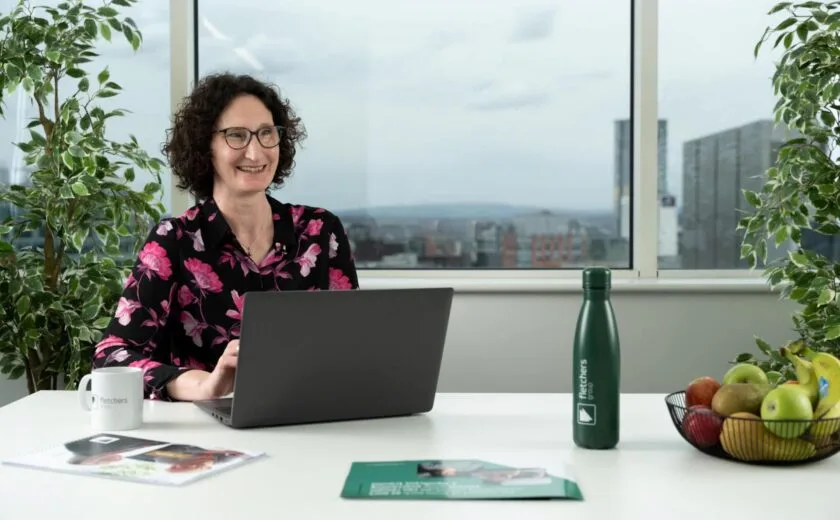 Mary Lomas seated at desk with laptop