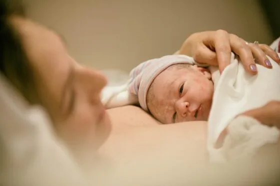 Newborn baby resting against parent