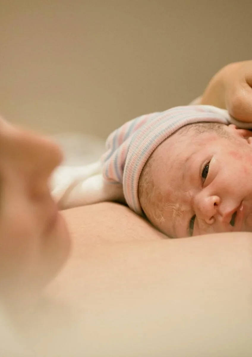 Newborn baby resting against parent