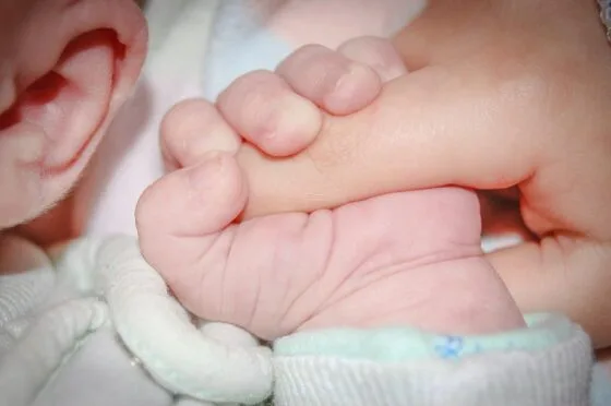 Newborn holding adult finger