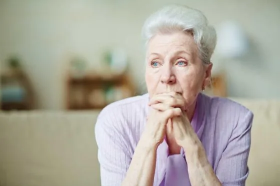 Older woman sitting thoughtfully at home