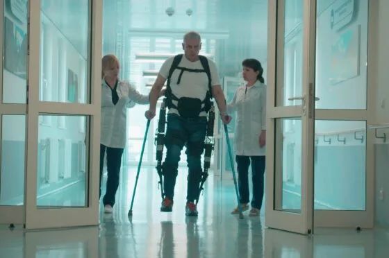 Patient using exoskeleton with clinicians in hospital