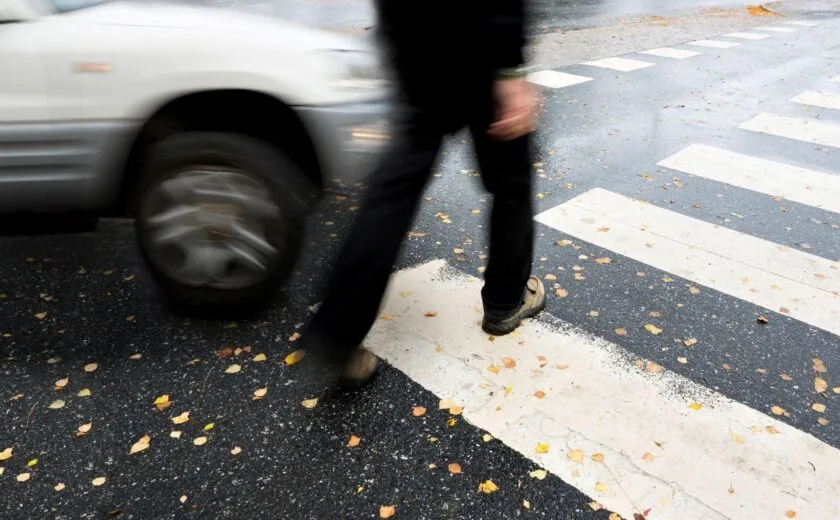 Pedestrian crossing road near passing car