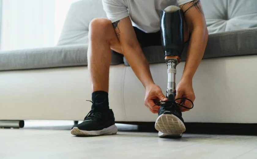 Person with prosthetic leg tying shoelace