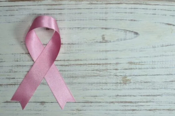 Pink breast cancer awareness ribbon on wooden surface