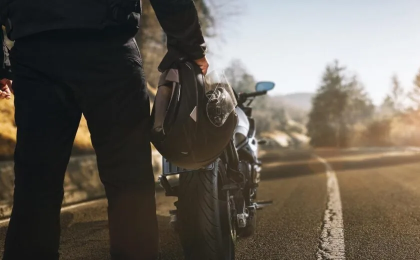 Rider holding helmet beside motorcycle