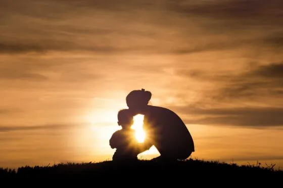Silhouette of child and adult at sunset