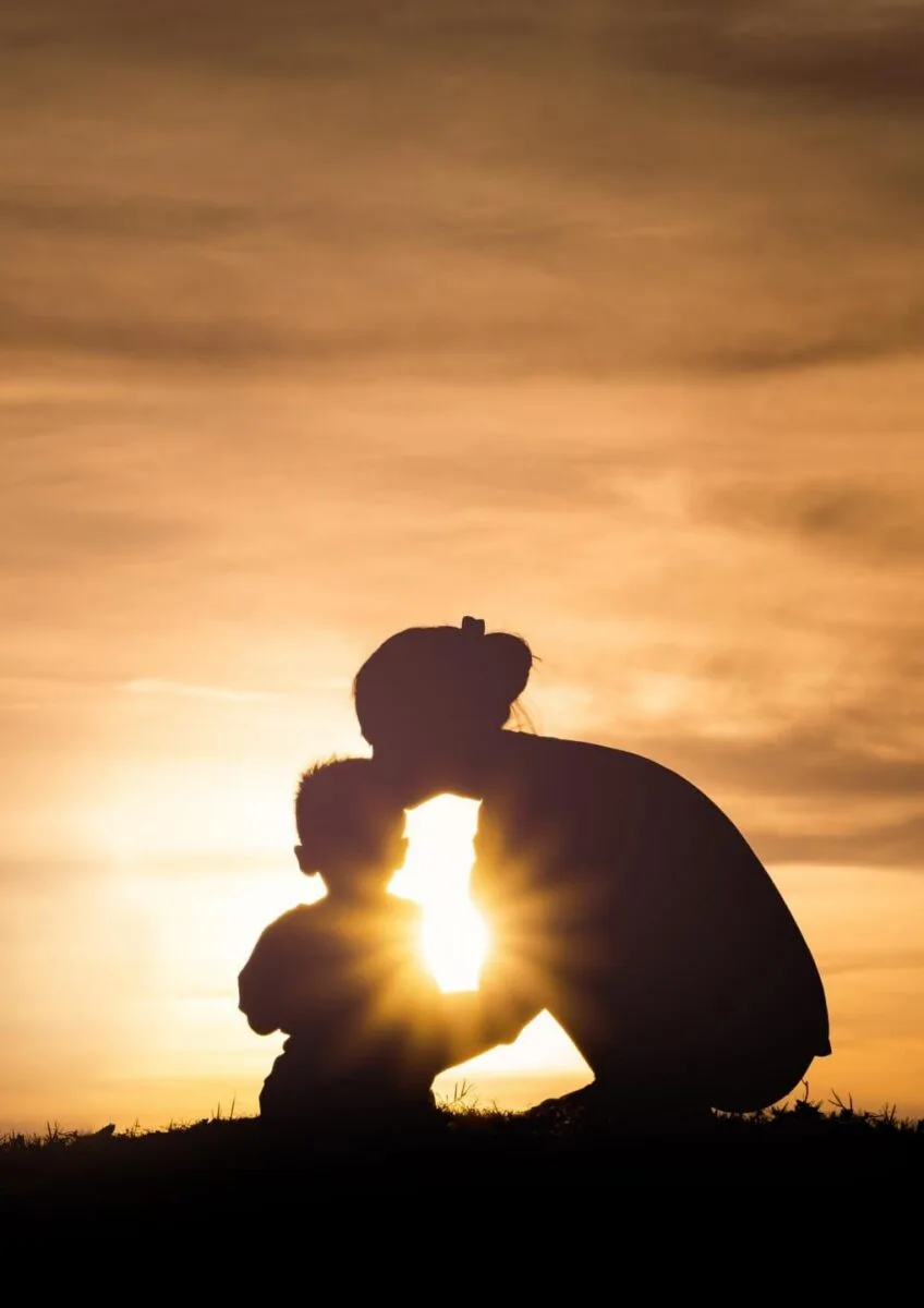 Silhouette of child and adult at sunset