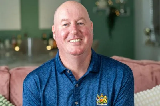Smiling man seated at home wearing blue polo shirt