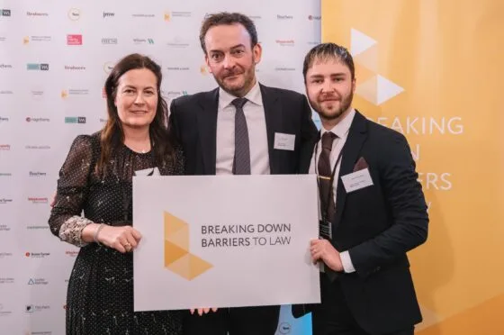 Three colleagues holding award at Breaking Down Barriers event