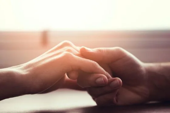 Two people holding hands in warm light