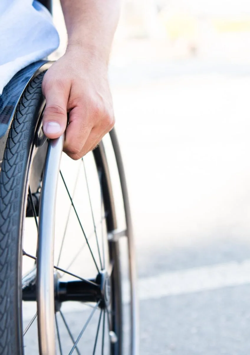 Wheelchair user holding wheel outdoors