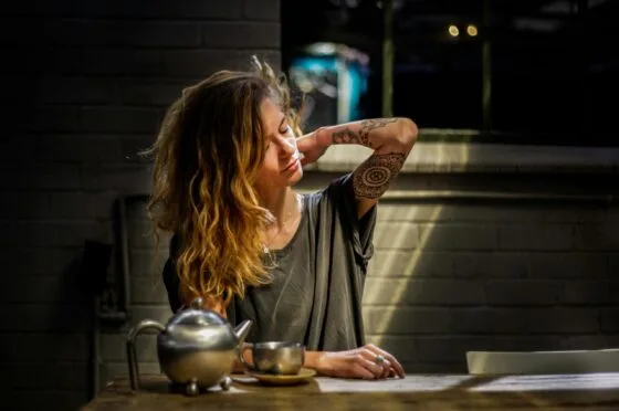 Woman clutching her back at kitchen table