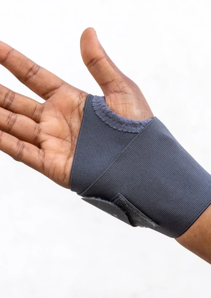 Hand wearing a grey wrist support brace against white background