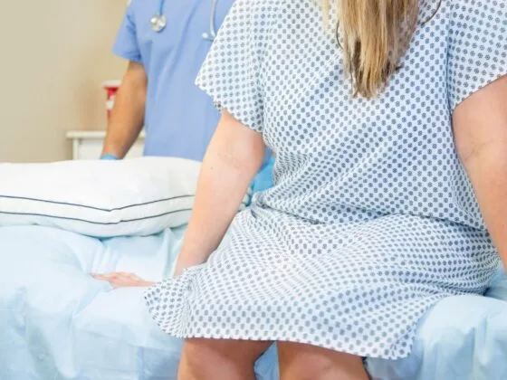 Patient sitting on hospital bed with medical staff in background